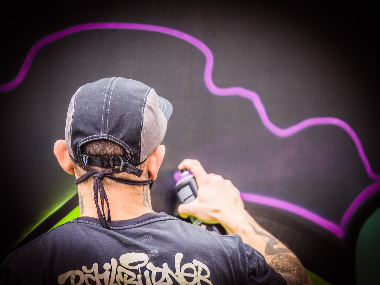 Street artist creating a large mural at an outdoor event