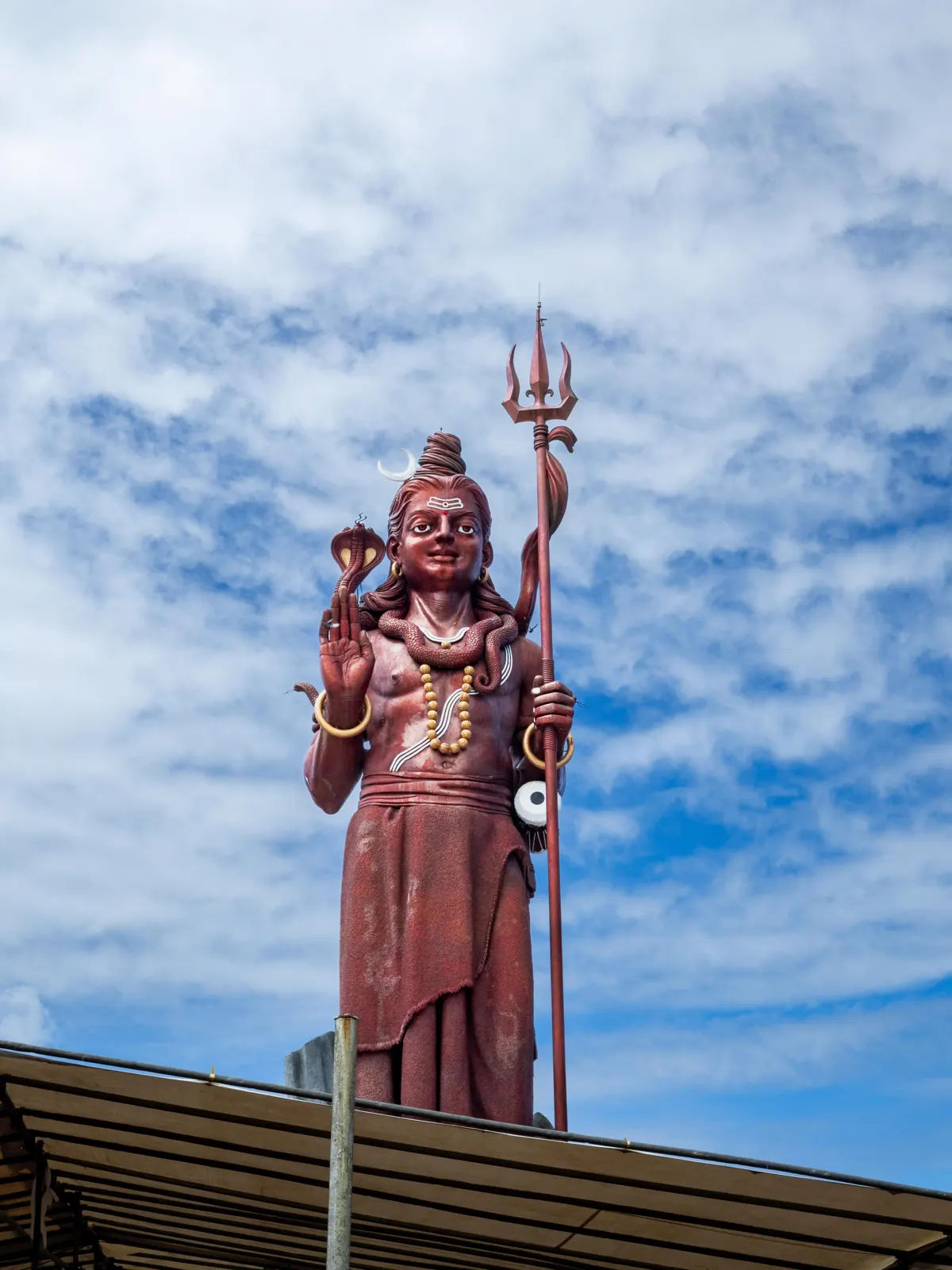 Mangal Mahadev, the Shiva statue at Grand Bassin, with trident and crescent moon against a blue sky.